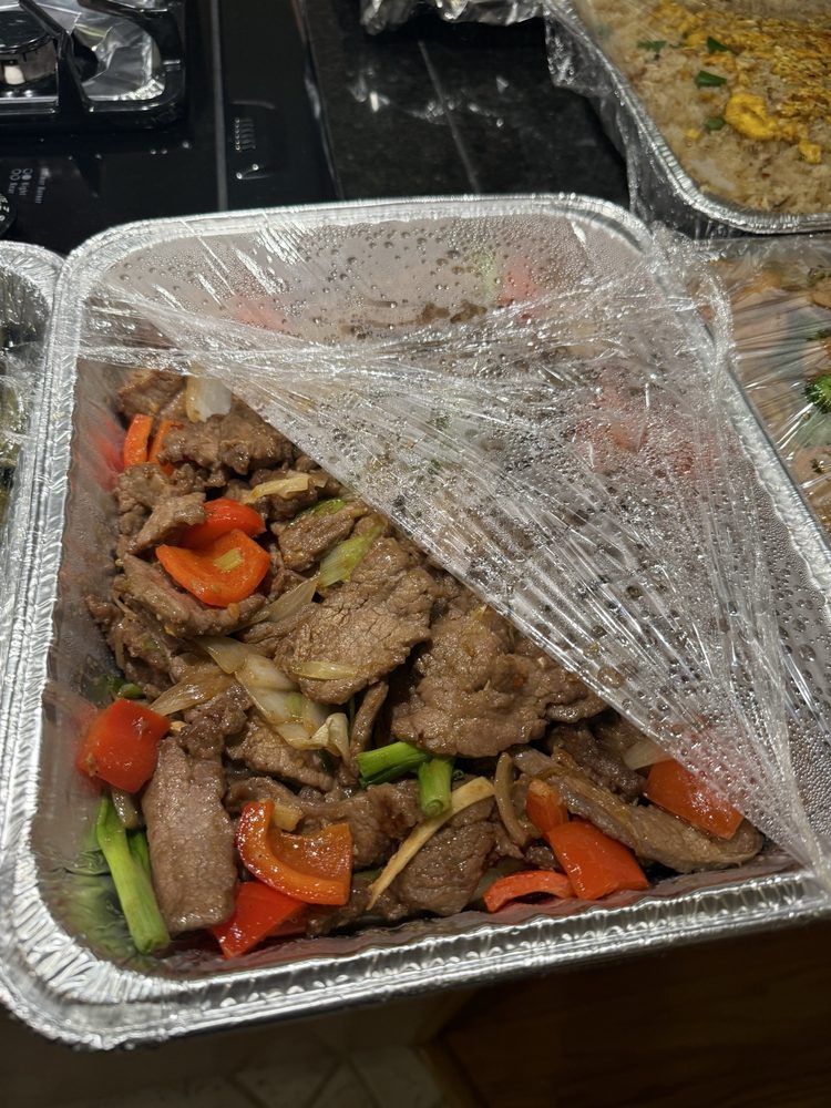 Mongolian beef with red peppers and green onions under plastic wrap