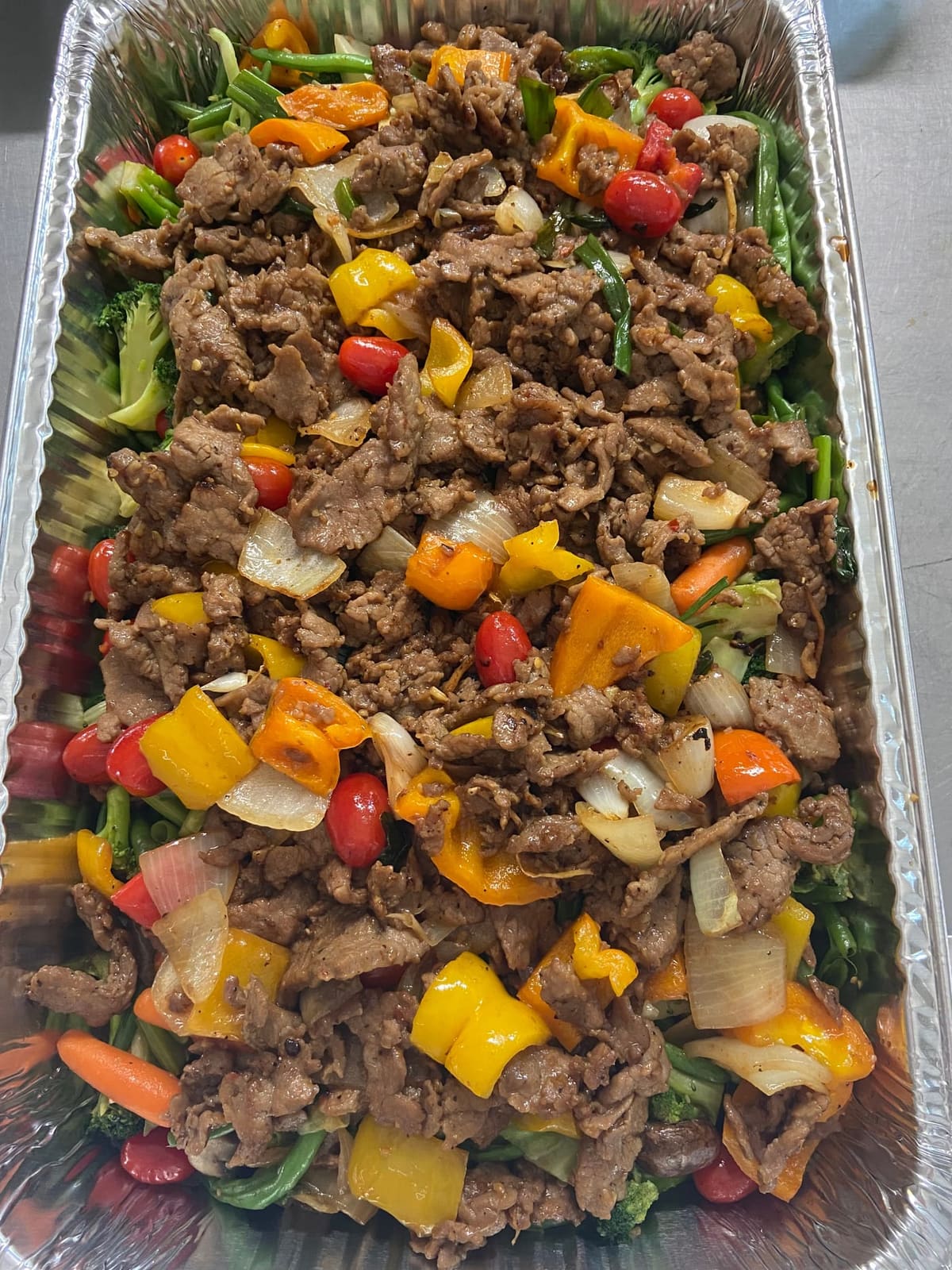 Full tray of Mongolian beef with onions, bell peppers and broccoli from Co Hoang Catering, ready for an Asian catering order